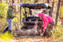 Two people with a deer and an off-road vehicle in a forest setting